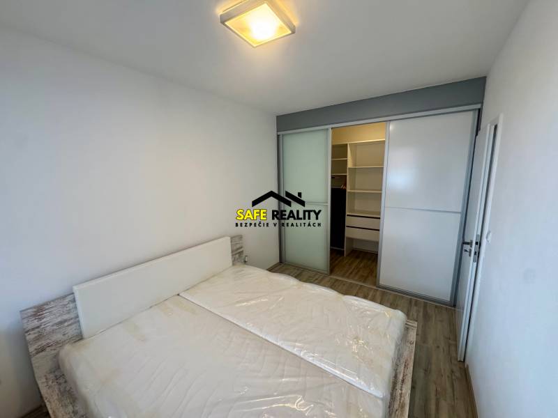 Hálószoba franciaággyal, beépített szekrénnyel és fa mintázatú padlóval egy kétszobás lakásban.