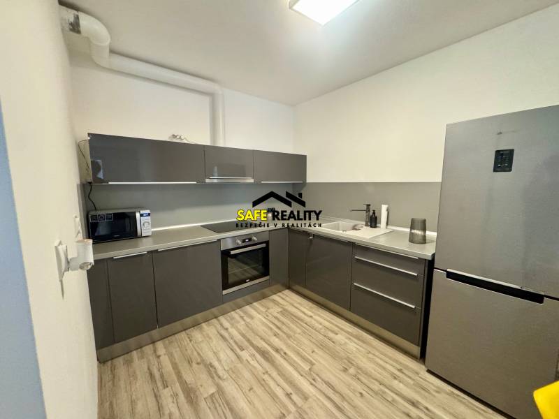 Konyha egy kétszobás lakásban, fa dekor padlóval és szürke konyhabútorral.