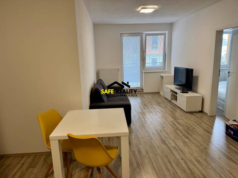 Nappali egy kétszobás lakásban fa dekor padlóval és világos ülőgarnitúrával.