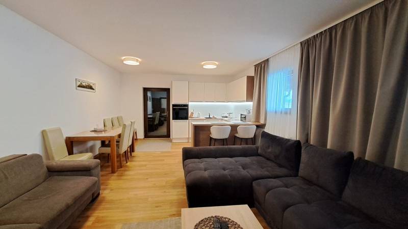 Nappali kétszobás lakásban konyhával, étkezőasztallal és fa dekorációjú padlóval.