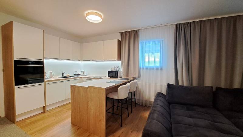 Konyha egy kétszobás lakásban bárpulttal és fa mintázatú padlóval.