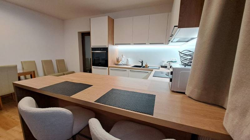 Konyha egy kétszobás lakásban beépített készülékekkel és fa hatású padlóval.