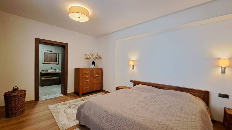 Hálószoba egy kétszobás lakásban ággyal, fa bútorokkal és fa dekorációjú padlóval.