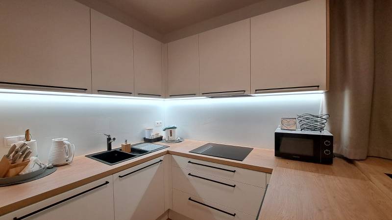 Konyha egy kétszobás lakásban fa dekorációval és főzőfelszereléssel.