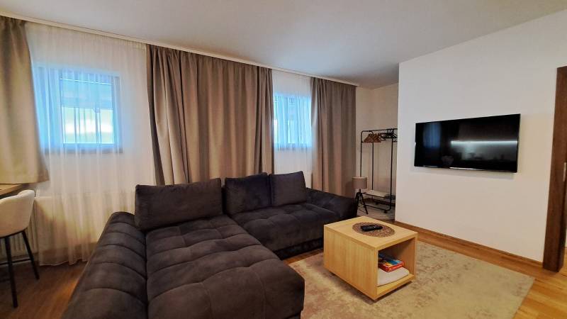 Nappali egy kétszobás lakásban kényelmes kanapéval és fa dekorációjú padlóval.