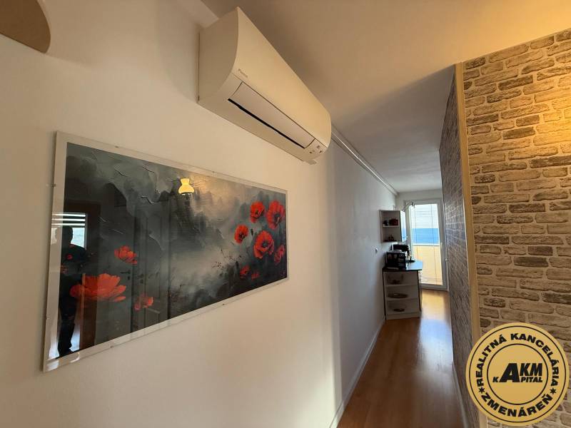 Folyosó egy 3 szobás lakásban, fa dekor padlóval, dekoratív téglafallal és légkondicionálóval.