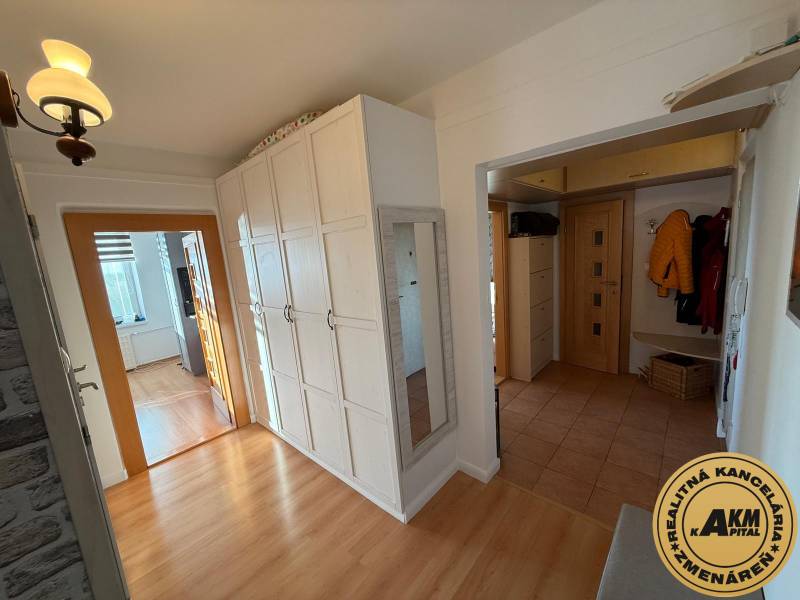 Folyosó egy 3 szobás lakásban, fa dekoros padlóval, fehér szekrényekkel és tükörrel.