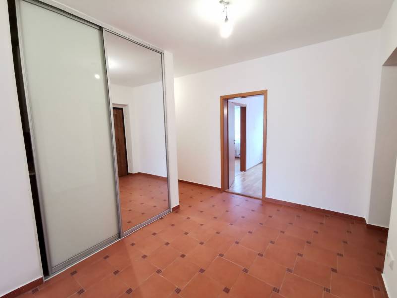 Folyosó egy 4 szobás lakásban csempével és beépített szekrénnyel tolóajtókkal.