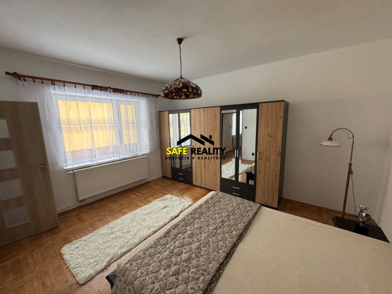 Hálószoba családi házban, fa dekorációjú padlóval, ággyal és ruhásszekrénnyel.