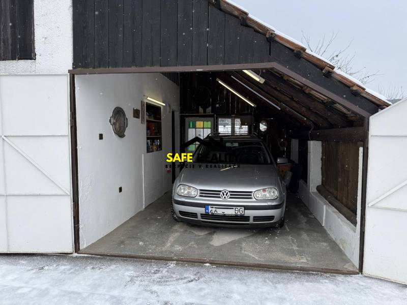 Garázs egy családi ház mellett Rosinán, télen parkoló autóval.