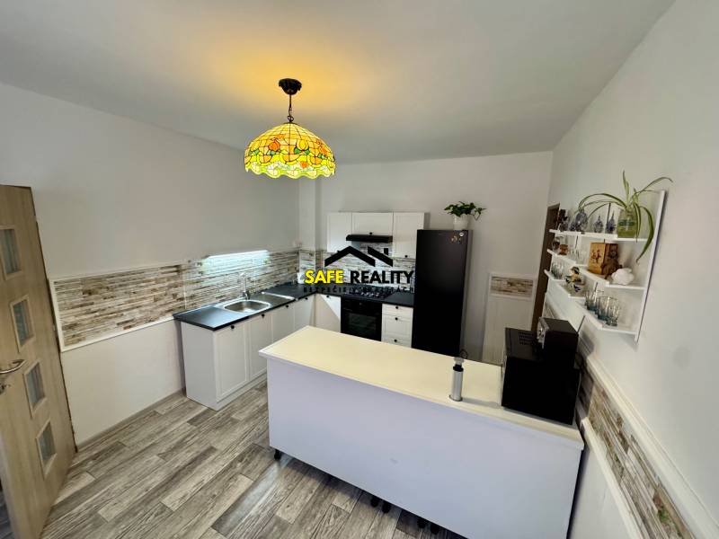 Konyha egy családi házban fa dekor padlóval, világítással és dekoratív burkolatokkal.