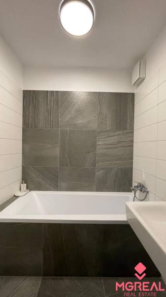 Fürdőszoba modern csempével és káddal egy kétszobás lakásban.