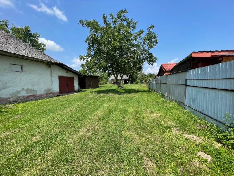 Kilátás egy zöld telekre Zemplínska Širokában, ideális lakhatásra, látható épületekkel.