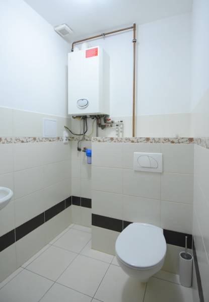 Fürdőszoba egy kétszobás lakásban kazánnal és WC-vel, kerámia csempével burkolva.