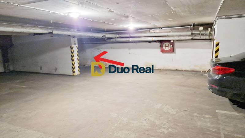 Földalatti parkolóhely a garázsokban, fal melletti parkolóhellyel és autókkal.