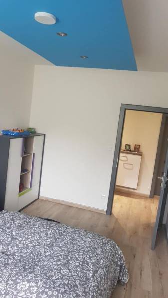 Szoba egy családi házban fa dekoros padlóval és kék mennyezettel.