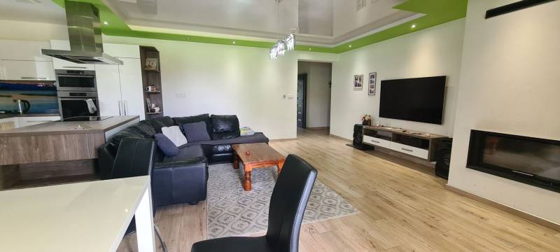 Nappali egy családi házban bőrkanapéval, televízióval és fa mintázatú padlóval.