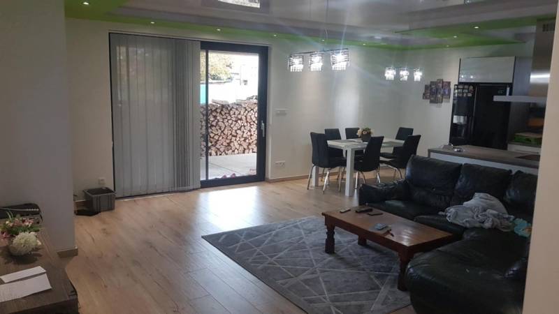 Nappali egy családi házban, fa mintázatú padlóval, kanapéval és étkezőasztallal.