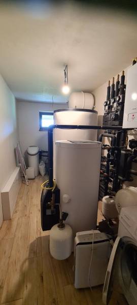 Családi ház kazánháza kazánnal, tartályokkal és fa dekorációjú padlóval.