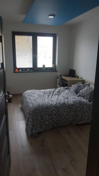 Hálószoba családi házban ággyal, íróasztallal és fa dekorációjú padlóval.