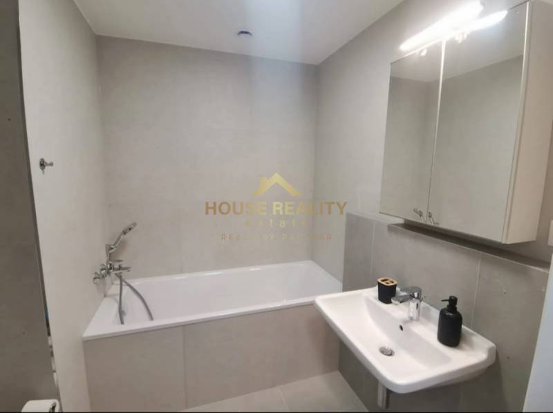 Fürdőszoba káddal és mosdóval egy egyszobás lakásban.