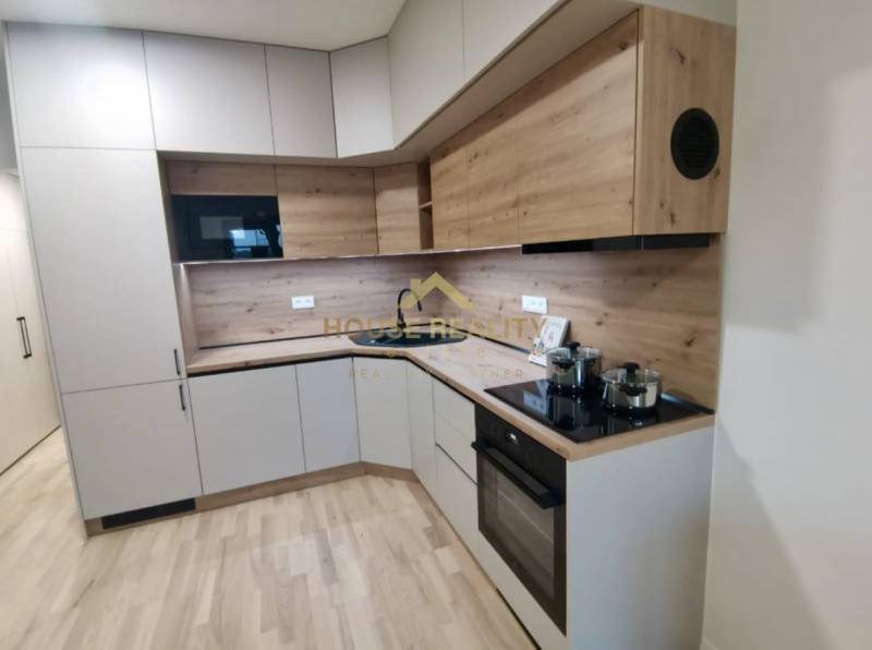 Konyha egy egyszobás lakásban, fa dekorációjú padlóval és modern készülékekkel.