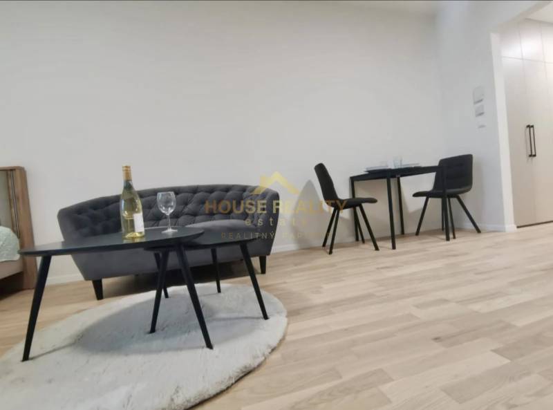 Nappali tér egy egyszobás lakásban kanapéval, asztallal és fa dekor padlóval.