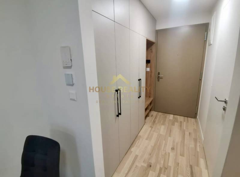 Folyosó egy egyszobás lakásban fehér szekrénnyel és fa mintázatú padlóval.