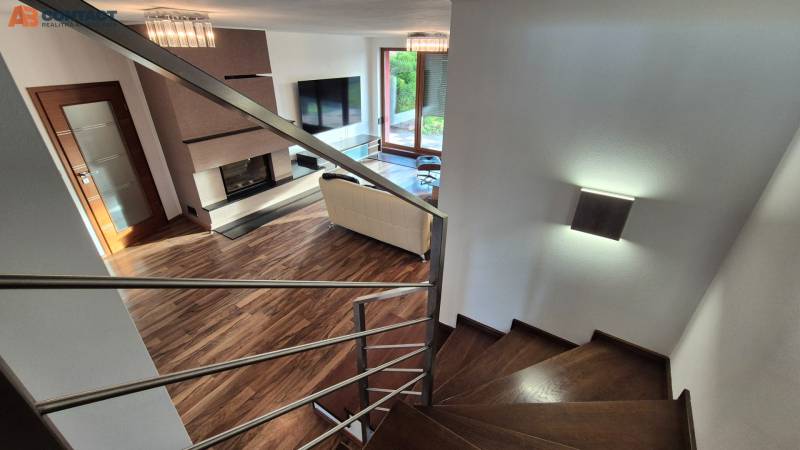 Nappali kandallóval és lépcsővel egy családi házban, fa dekorációjú padlóval.