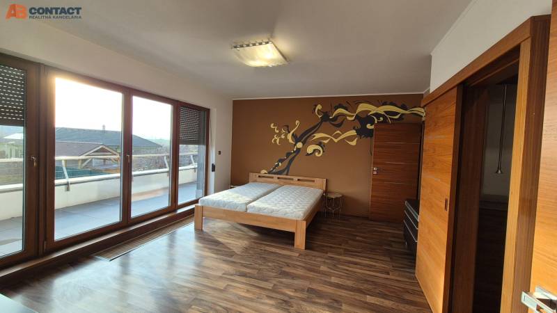 Szoba egy családi házban fa hatású padlóval, franciaággyal és terasszal.