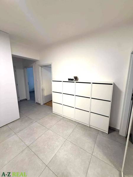 Tágas folyosó világos csempékkel és fehér komóddal egy 4 szobás lakásban.