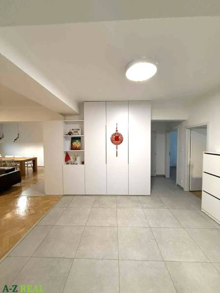 Folyosó egy 4 szobás lakásban fehér beépített szekrényekkel és kerámia padlólapokkal.