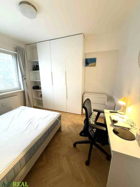 Hálószoba egy 4 szobás lakásban fehér bútorokkal és fa dekorációjú padlóval.