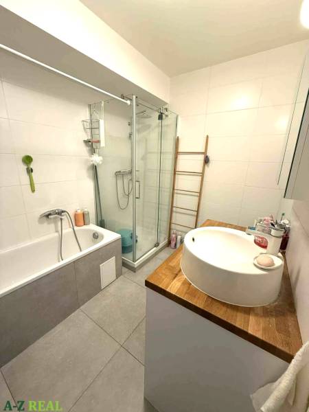 Fürdőszoba káddal, zuhanyzóval és mosdóval egy fa pulton a négy szobás lakásban.