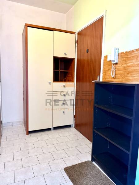 Az egyszobás lakás folyosója csempével, szekrényekkel és telefonnal a falon.