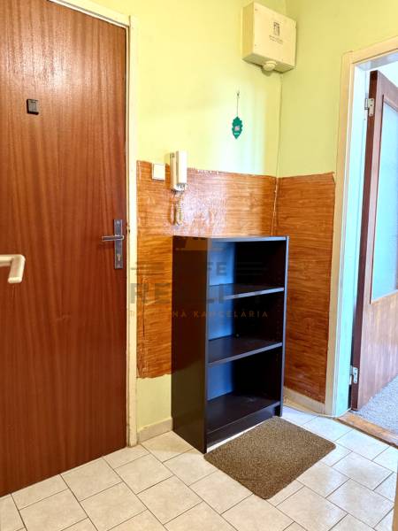 Egy szobás lakás előszobája szekrénnyel, csempével és telefonnal a falon.