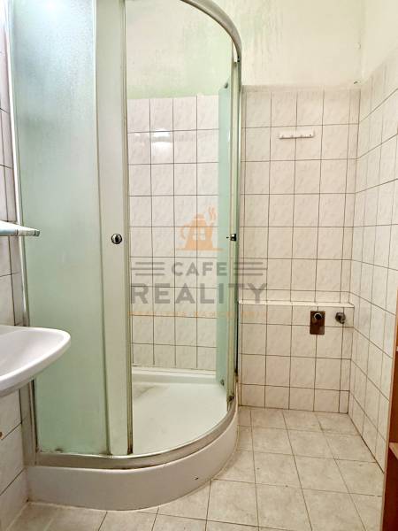 Fürdőszoba zuhanyzóval és csempével az egyszobás lakásban.