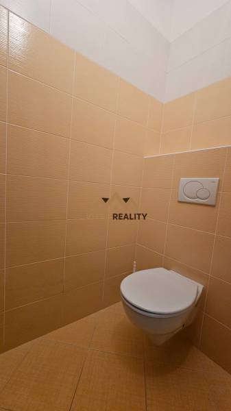 Bézs csempékkel ellátott mosdó üzlethelyiségben.