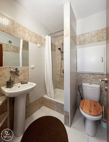 Fürdőszoba zuhanyzóval, mosdóval és WC-vel egy egyszobás lakásban.