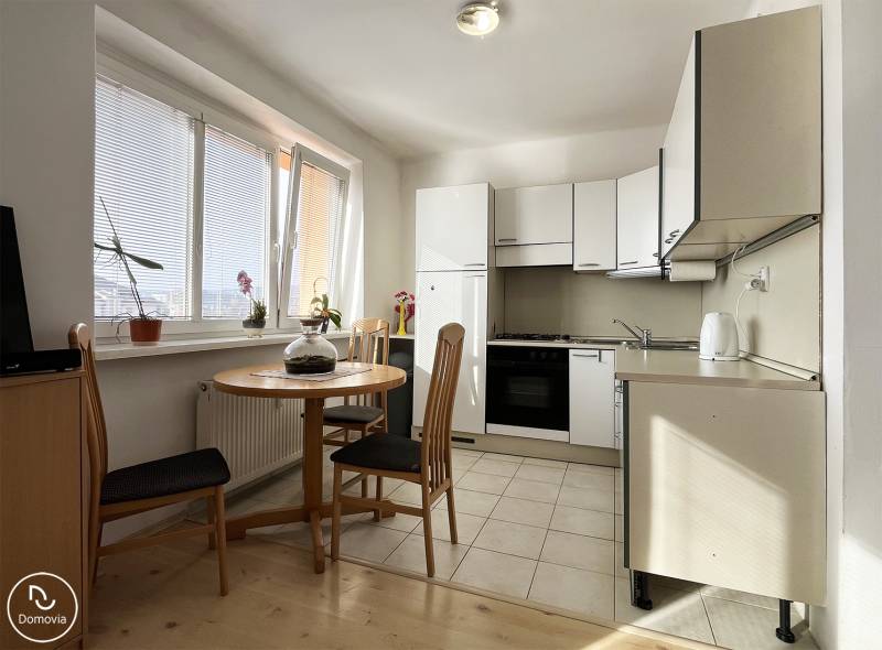 Konyha egy egyszobás lakásban, kerek asztallal és fa dekorációjú padlóval.