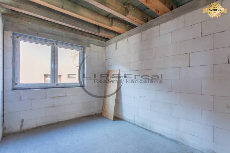 Fehér falakkal és nagy ablaknyílással rendelkező épület.