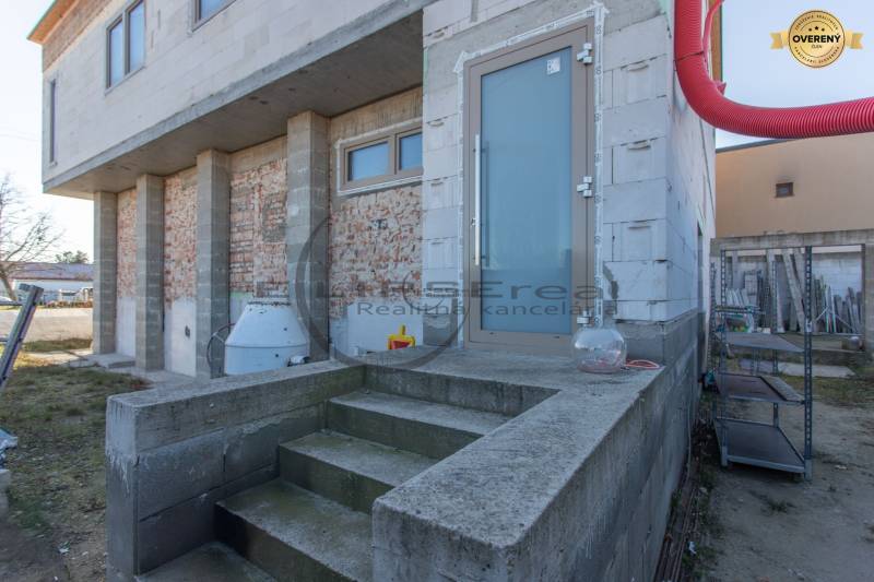 Egy épület Nagylévárdon befejezetlen homlokzattal és beton alapú lépcsőkkel.