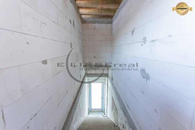 Kilátás egy lépcsőházra egy épületben betonfalakkal és egy ablakkal a végén.