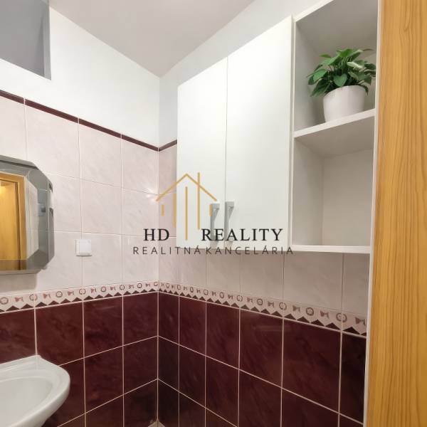 Fürdőszoba egy kétszobás lakásban kerámia burkolattal és tükörrel a mosdó felett.