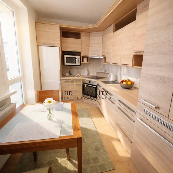 Konyha egy kétszobás lakásban fa dekorációval, étkezőasztallal és modern készülékekkel.