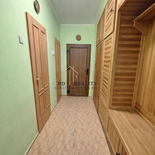 Folyosó egy kétszobás lakásban fa dekorációval és zöld falakkal.