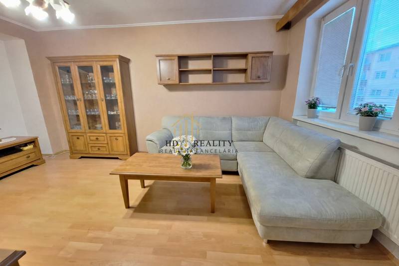 Nappali egy kétszobás lakásban sarokkanapéval, a fa dekoráció kiegészíti a belső teret.