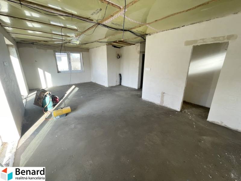 Családi ház belső tere befejezetlen padlóval és félkész mennyezettel.