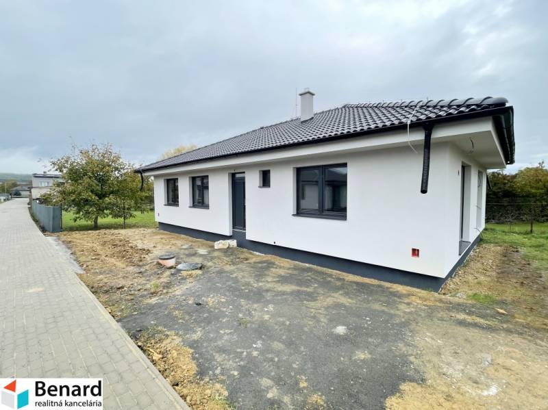 Családi ház Solban fehér homlokzattal és ferde tetővel, kerttel körülvéve.