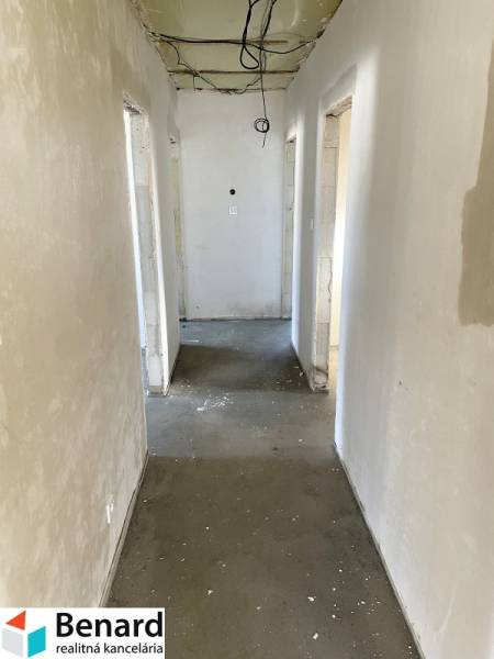 Egy családi ház folyosója befejezetlen mennyezettel és betonpadlóval.